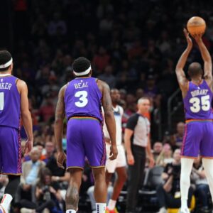 Phoenix Suns guard Devin Booker (1) and Phoenix Suns guard Bradley Beal (3) watch as Phoenix Suns forward Kevin Durant (35) shoots a free throw against the Minnesota Timberwolves during the first half at Footprint Center.