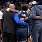 Dallas Mavericks guard Kyrie Irving (11) is helped off the court by forward Naji Marshall (13) and forward Anthony Davis (3) during the second quarter against the Sacramento Kings at the American Airlines Center
