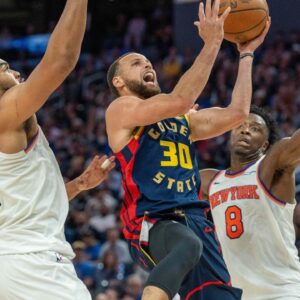 Golden State Warriors guard Stephen Curry (30) shoots a layup against New York Knicks center Karl-Anthony Towns (32) during the fourth quarter at Chase Center
