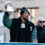 Feb 14, 2025; Philadelphia, PA, USA; Philadelphia Eagles running back Saquon Barkley (26) celebrates next to team owner Jeffrey Lurie and quarterback Jalen Hurts (1) during the Super Bowl LIX championship parade and rally.