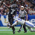 Colorado Buffaloes quarterback Shedeur Sanders (2) attempts a pass as Brigham Young Cougars defensive end Tyler Batty (92) attempts to make a tackle during the third quarter at Alamodome.