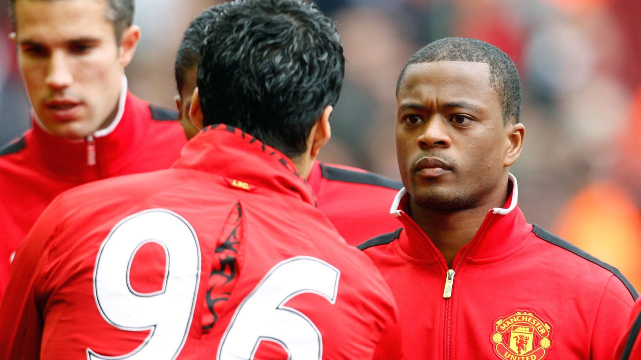 Manchester Uniteds Patrice Evra (R) shakes hands with Liverpools Luis Suarez before kick off .