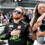 NASCAR Cup Series driver Tyler Reddick (45) stands with his wife, Alexa DeLeon Reddick, and son, Beau, during the national anthem ahead of the Brickyard 400, Sunday, July 21, 2024, at Indianapolis Motor Speedway.