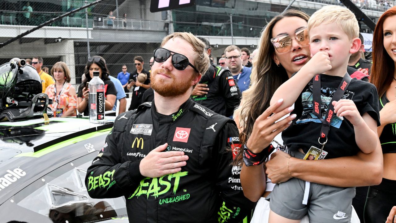 NASCAR Cup Series driver Tyler Reddick (45) stands with his wife, Alexa DeLeon Reddick, and son, Beau, during the national anthem ahead of the Brickyard 400, Sunday, July 21, 2024, at Indianapolis Motor Speedway.