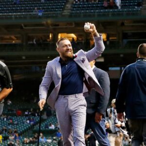 MMA fighter Conor McGregor waves to fans as he walks off the field before the game between the Chicago Cubs and the Minnesota Twins at Wrigley Field.