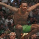 Israel Adesanya (red gloves) reacts before a bout against Jared Cannonier (blue gloves) during UFC 276 at T-Mobile Arena.