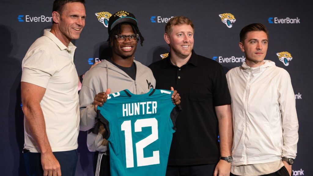 Jacksonville Jaguars first round draft pick Travis Hunter poses for a photo with executive vice president of football operations Tony Boselli, head coach Liam Coen, and general manager James Gladstone, during a press conference at Miller Electric Center.