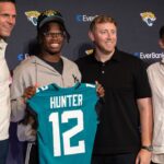 Jacksonville Jaguars first round draft pick Travis Hunter poses for a photo with executive vice president of football operations Tony Boselli, head coach Liam Coen, and general manager James Gladstone, during a press conference at Miller Electric Center.