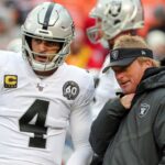 Oakland Raiders head coach Jon Gruden talks with quarterback Derek Carr (4) before the game against the Kansas City Chiefs at Arrowhead Stadium.