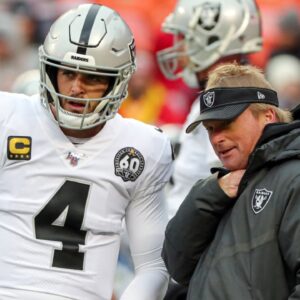Oakland Raiders head coach Jon Gruden talks with quarterback Derek Carr (4) before the game against the Kansas City Chiefs at Arrowhead Stadium.