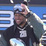 Eagles running back Saquon Barkley, center, holds the Vince Lombardi trophy during the Eagles Super Bowl championship parade on Friday, Feb. 14, 2025.