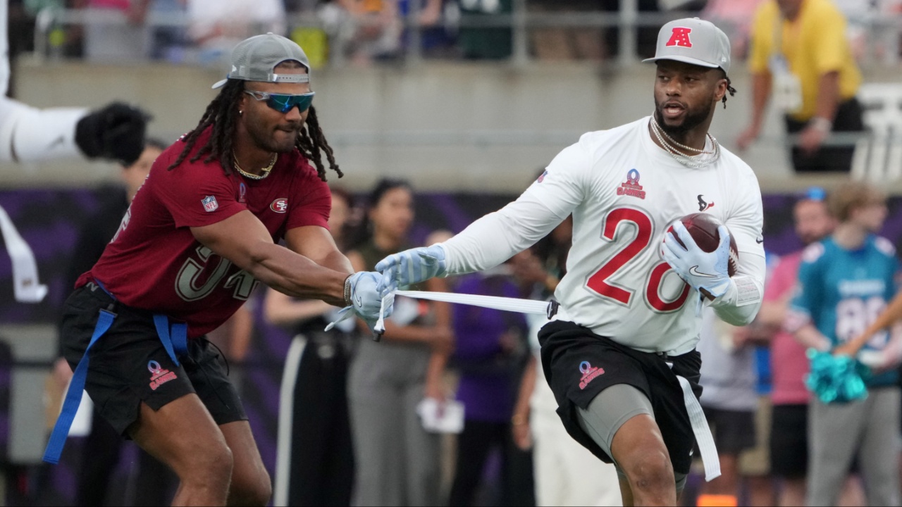 AFC running back Joe Mixon of the Houston Texans (28) carries the ball against NFC linebacker Fred Warner of the San Francisco 49ers (54) during the 2025 Pro Bowl Games flag football game at Camping World Stadium.