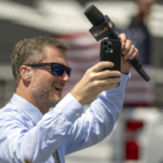 Dale Earnhardt Jr. raises his hands to cheering fans on the grid before the Verizon 200 at the Indianapolis Motor Speedway Road Course.