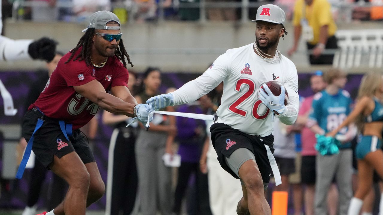 AFC running back Joe Mixon of the Houston Texans (28) carries the ball against NFC linebacker Fred Warner of the San Francisco 49ers (54) during the 2025 Pro Bowl Games at Camping World Stadium.