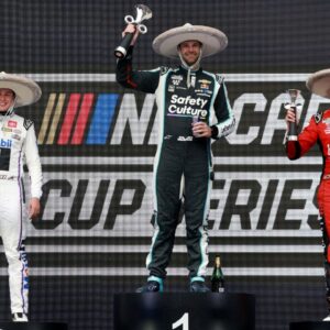 Shane van Gisbergen celebrates on the podium after winning the NASCAR Cup Series Mexico alongside second place driver Christopher Bell and third place driver Chase Elliott during the NASCAR Cup Series Mexico City Race at Autodromo Hermanos Rodriguez.