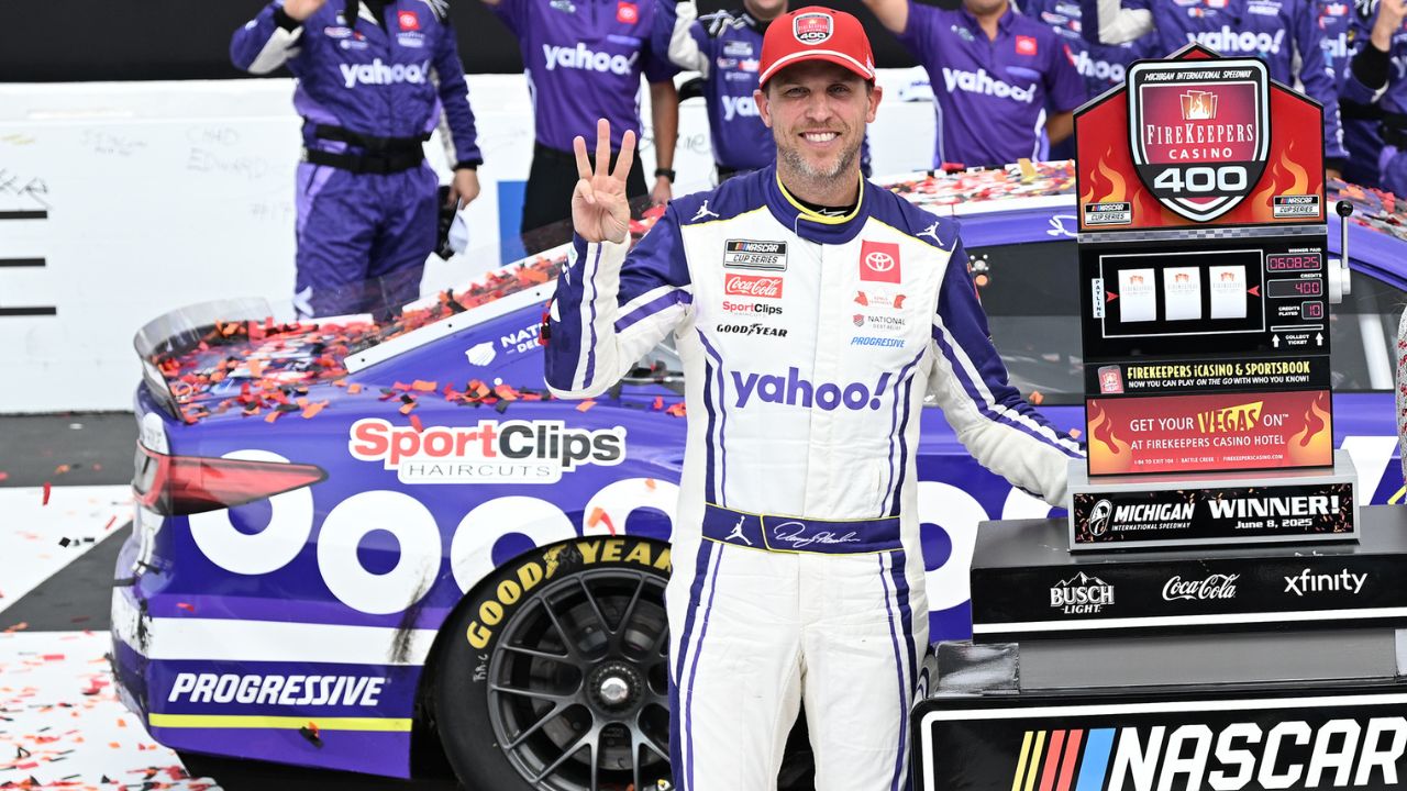 NASCAR Cup Series driver Denny Hamlin (11) celebrates with his team, holding up three fingers, one for each of his victories at Michigan International Speedway, after winning the FireKeepers Casino 400.