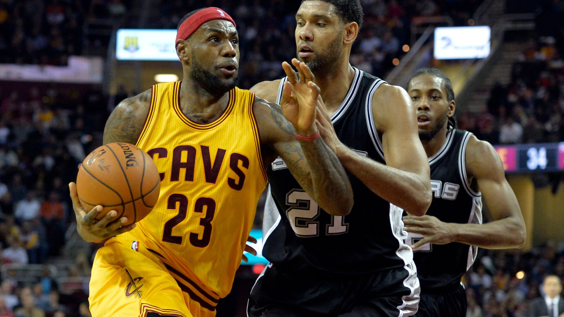 Nov 19, 2014; Cleveland, OH, USA; Cleveland Cavaliers forward LeBron James (23) drives against San Antonio Spurs forward Tim Duncan (21) and forward Kawhi Leonard (2) in the second quarter at Quicken Loans Arena