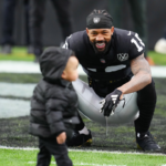 Jan 5, 2025; Paradise, Nevada, USA; Las Vegas Raiders cornerback Jack Jones (18) plays with his son before the start of a game against the Los Angeles Chargers at Allegiant Stadium. Mandatory Credit: Stephen R. Sylvanie-Imagn Images