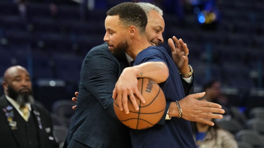 Charlotte Hornets color commentator Dell Curry (left) and Golden State Warriors guard Stephen Curry (right) hug before the game at Chase Center.