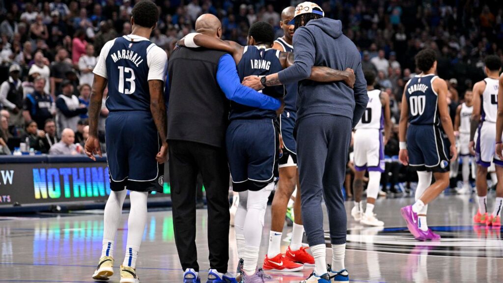 Dallas Mavericks guard Kyrie Irving (11) is helped off the court by forward Naji Marshall (13) and forward Anthony Davis (3) during the second quarter against the Sacramento Kings at the American Airlines Center.