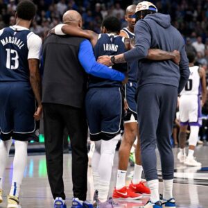 Dallas Mavericks guard Kyrie Irving (11) is helped off the court by forward Naji Marshall (13) and forward Anthony Davis (3) during the second quarter against the Sacramento Kings at the American Airlines Center.