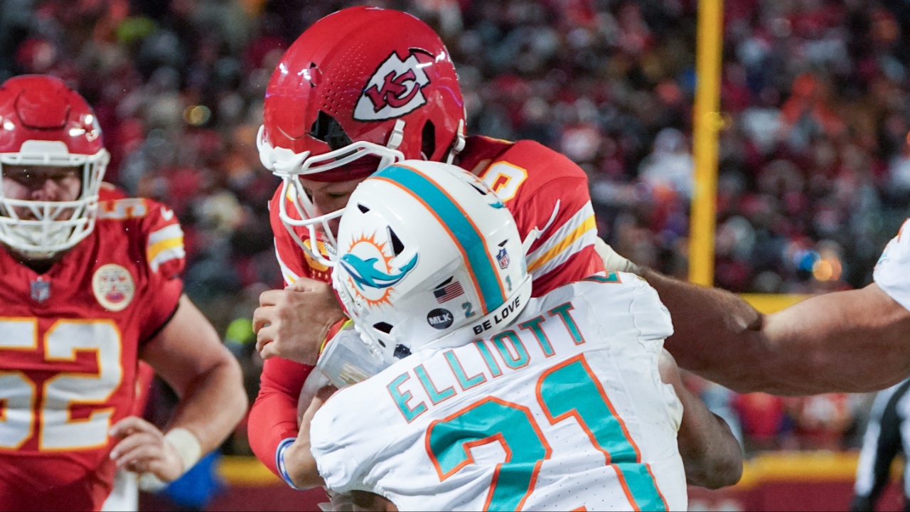 The helmet of Kansas City Chiefs quarterback Patrick Mahomes (15) cracks during his run as Miami Dolphins safety DeShon Elliott (21) makes contact in a 2024 AFC wild card game at GEHA Field at Arrowhead Stadium.