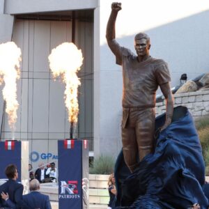 Retired New England Patriot Hall of Famer Tom Brady stands with Jonathan and Robert Kraft during a statue unveiling before a game against the Washington Commanders at Gillette Stadium.