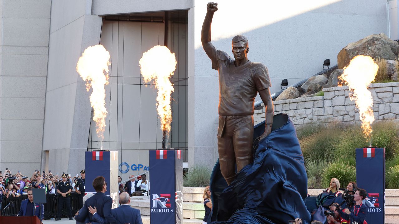 Retired New England Patriot Hall of Famer Tom Brady stands with Jonathan and Robert Kraft during a statue unveiling before a game against the Washington Commanders at Gillette Stadium.
