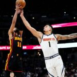 Atlanta Hawks guard Trae Young (11) and Denver Nuggets forward Michael Porter Jr. (1) reach for the ball in the second quarter at Ball Arena.