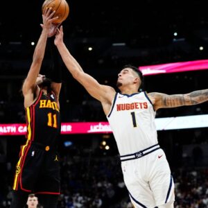 Atlanta Hawks guard Trae Young (11) and Denver Nuggets forward Michael Porter Jr. (1) reach for the ball in the second quarter at Ball Arena.