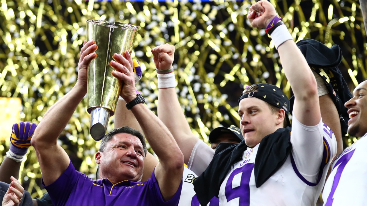LSU Tigers head coach Ed Orgeron hoists the national championship trophy with quarterback Joe Burrow after a victory against the Clemson Tigers in the College Football Playoff national championship game at Mercedes-Benz Superdome.