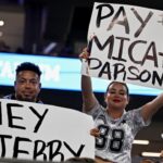 Dallas Cowboys fans hold up signs to owner Jerry Jones and defensive end Micah Parsons (11) during the second half of the game against the Baltimore Ravens at AT&T Stadium.