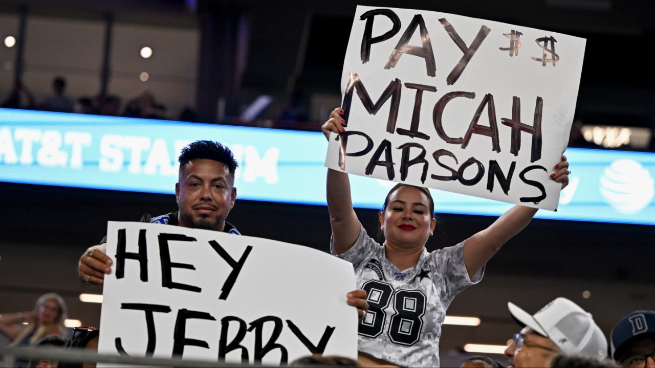 Dallas Cowboys fans hold up signs to owner Jerry Jones and defensive end Micah Parsons (11) during the second half of the game against the Baltimore Ravens at AT&T Stadium.