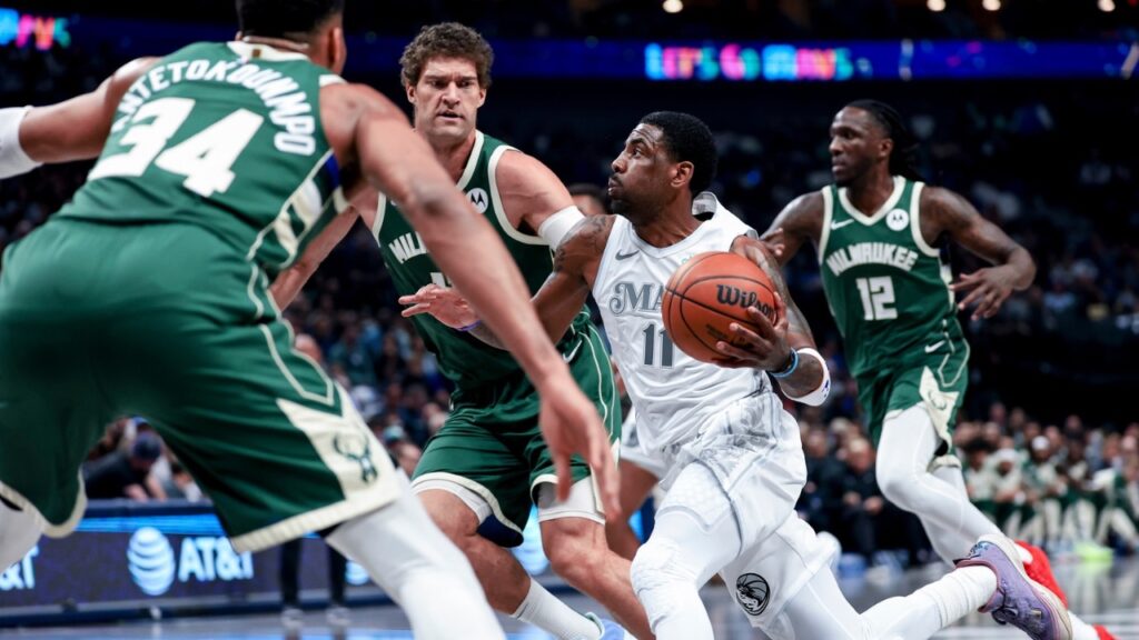 Dallas Mavericks guard Kyrie Irving (11) drives to the basket as Milwaukee Bucks center Brook Lopez (11) and Milwaukee Bucks forward Giannis Antetokounmpo (34) defend during the first half at American Airlines Center.