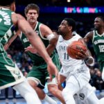 Dallas Mavericks guard Kyrie Irving (11) drives to the basket as Milwaukee Bucks center Brook Lopez (11) and Milwaukee Bucks forward Giannis Antetokounmpo (34) defend during the first half at American Airlines Center.