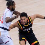 Devin Booker 1 of the Phoenix Suns fends off Derrick Jones Jr. 55 of the Los Angeles Clippers during their regular season NBA