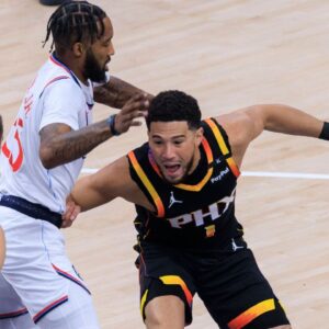 Devin Booker 1 of the Phoenix Suns fends off Derrick Jones Jr. 55 of the Los Angeles Clippers during their regular season NBA