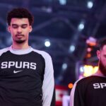 Dec 13, 2024; Portland, Oregon, USA; San Antonio Spurs center Victor Wembanyama (1), left, stands with forward Sandro Mamukelashvili (54) during the singing of the national anthem before a game against the Portland Trail Blazers at Moda Center. Mandatory Credit: Troy Wayrynen-Imagn Images