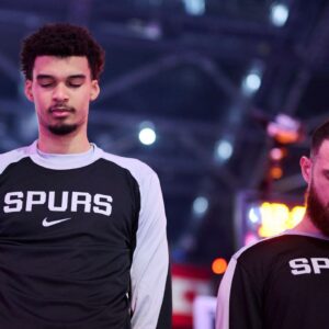 Dec 13, 2024; Portland, Oregon, USA; San Antonio Spurs center Victor Wembanyama (1), left, stands with forward Sandro Mamukelashvili (54) during the singing of the national anthem before a game against the Portland Trail Blazers at Moda Center. Mandatory Credit: Troy Wayrynen-Imagn Images