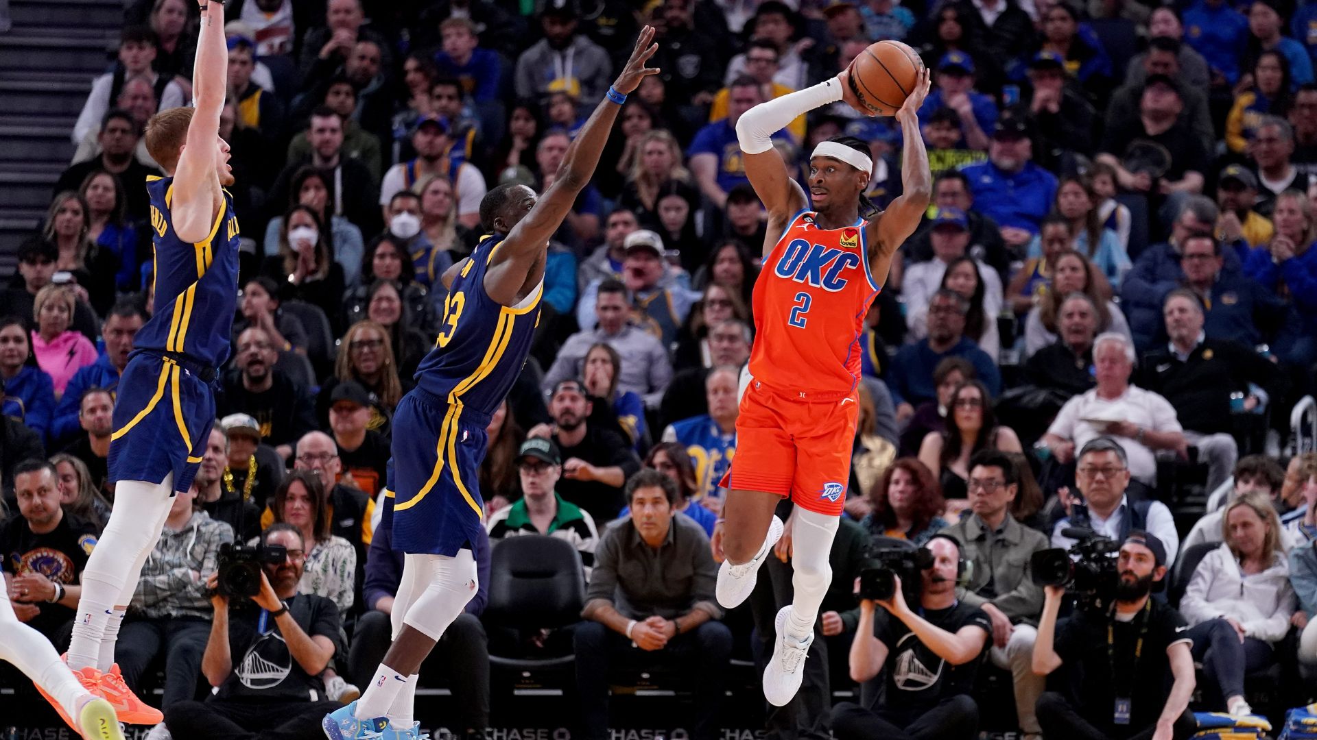Apr 4, 2023; San Francisco, California, USA; Oklahoma City Thunder guard Shai Gilgeous-Alexander (2) passes the ball around the reach of Golden State Warriors forward Draymond Green (23) and guard Donte DiVincenzo (0) in the fourth quarter at the Chase Center.