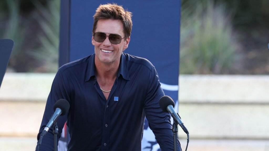 Retired New England Patriot Hall of Famer Tom Brady speaks during a statue unveiling before a game against the Washington Commanders at Gillette Stadium. Mandatory