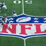 A general overall view as New York Jets quarterback Justin Fields (7) throws the ball at midfield on the NFL shield logo in the first quarter against the Denver Broncos during an NFL International Series game at Tottenham Hotspur Stadium.