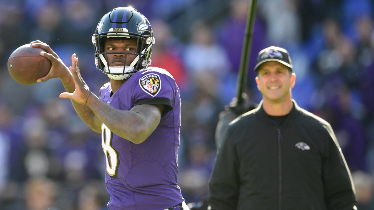 Baltimore Ravens quarterback Lamar Jackson (8) passes as head coach John Harbaugh looks prior to the game against the Los Angeles Chargers in a AFC Wild Card playoff football game at M&T Bank Stadium.