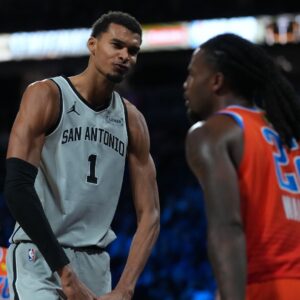 Dec 13, 2025; Las Vegas, Nevada, USA; San Antonio Spurs forward Victor Wembanyama (1) flexes in front of Oklahoma City Thunder guard Cason Wallace (22) during the third quarter at T-Mobile Arena.