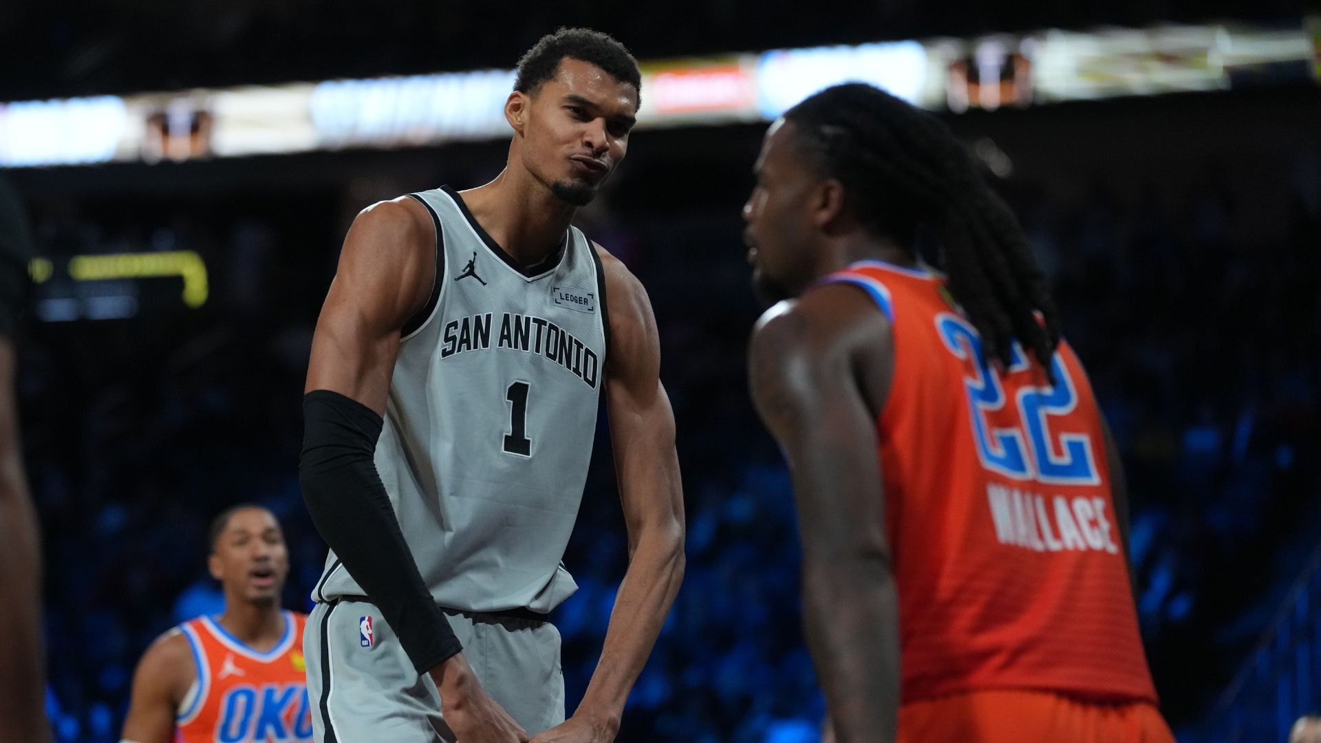 Dec 13, 2025; Las Vegas, Nevada, USA; San Antonio Spurs forward Victor Wembanyama (1) flexes in front of Oklahoma City Thunder guard Cason Wallace (22) during the third quarter at T-Mobile Arena.