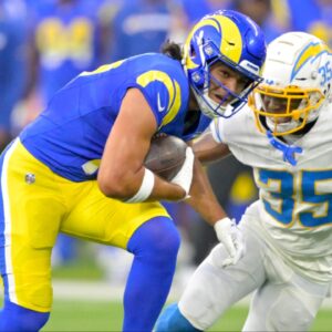 Los Angeles Rams wide receiver Puka Nacua (17) hangs on the the ball before he is stopped by Los Angeles Chargers cornerback AJ Uzodinma (35) in the first half at SoFi Stadium.