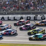 Oct 19, 2025; Talladega, Alabama, USA; Cars race by Talladega signage during stage one of the YellaWood 500 at Talladega Superspeedway