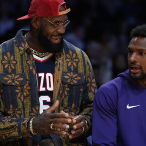 Oct 24, 2025; Los Angeles, California, USA; Los Angeles Lakers forward LeBron James (left) and son Bronny James watch from the bench in the second half against the Minnesota Timberwolves at Crypto.com Arena