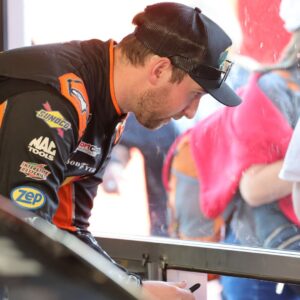 Feb 13, 2026; Daytona Beach, Florida, USA; NASCAR Cup Series driver Chase Briscoe (19) signs autographs during NASCAR Cup Series practice at Daytona International Speedway