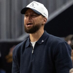 Golden State Warriors guard Stephen Curry (in white baseball hat) cheers on his team against the Los Angeles Clippers during the second quarter at Chase Center.